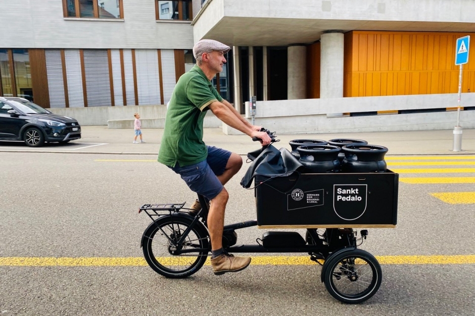 Mann fährt mit dem E-Cargobike auf einer Strasse